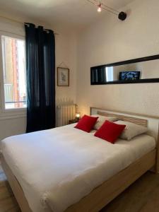 1 dormitorio con 1 cama blanca grande con almohadas rojas en F2 Résidence Eurotel n°1 avec vue sur le Cher, Centre - Ville en Montluçon