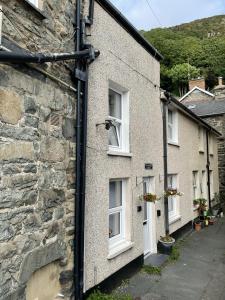 a stone house with white windows on a street at Glanywerydd Cottage in Barmouth