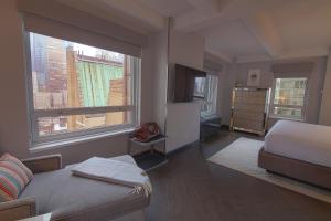 a bedroom with a bed and a tv and two windows at Hotel Edison Times Square in New York