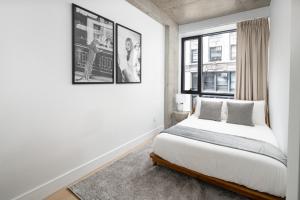 a white bedroom with a bed and a window at Perfectly located 2BD Penthouse in Chelsea in New York