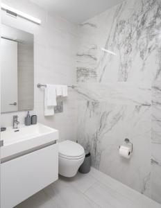 a white bathroom with a toilet and a sink at Perfectly located 2BD Penthouse in Chelsea in New York