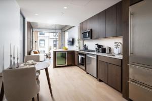 uma cozinha com armários de madeira e uma mesa num quarto em Perfectly located 2BD Penthouse in Chelsea em Nova Iorque
