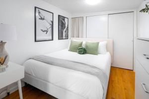 a white bedroom with a white bed with green pillows at Stylish One-Bedroom with In-unit Laundry in East Village in New York