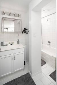 a white bathroom with a sink and a bath tub at Stylish One-Bedroom with In-unit Laundry in East Village in New York