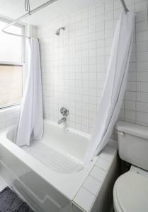 a white bathroom with a tub and a toilet at Stylish One-Bedroom with In-unit Laundry in East Village in New York
