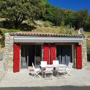 a table and chairs in front of a building with red doors at Maison confortable avec piscine à Saint-Julien-de-la-Nef in Saint-Julien-de-la-Nef