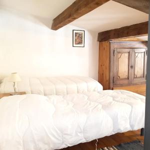 a white bed in a room with a wooden ceiling at Maison confortable avec piscine à Saint-Julien-de-la-Nef in Saint-Julien-de-la-Nef