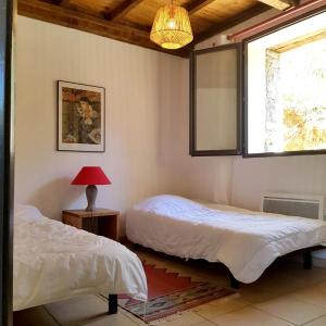 a bedroom with two beds and a window and a lamp at Maison confortable avec piscine à Saint-Julien-de-la-Nef in Saint-Julien-de-la-Nef