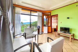 a living room with a table and chairs and a television at Arenal Garden Lodge in El Castillo de La Fortuna