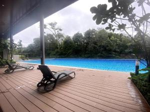 two chairs sitting on a deck next to a swimming pool at Modern Apartment in WP Putrajaya in Putrajaya