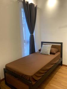 a bed in a room with a window with a curtain at Modern Apartment in WP Putrajaya in Putrajaya