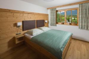 Un dormitorio con una cama grande con una pared de madera. en Ferienwohnung Unteröd, en Schönau am Königssee