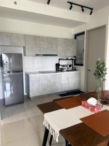a kitchen with a stainless steel refrigerator and a table at Modern Apartment in WP Putrajaya in Putrajaya