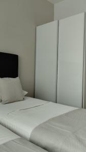 a white bedroom with a large white bed with a headboard at inas 2 bedroom apartment in Lefkimmi