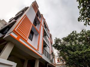 un edificio naranja y blanco con árboles en el primer plano en Super OYO Flagship Rajbanshi Nagar en Patna