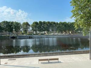 um banco de parque sentado ao lado de um lago com árvores em F2 Résidence Eurotel n°5 avec vue sur le Cher, Centre - Ville em Montluçon