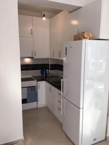 a kitchen with white cabinets and a white refrigerator at Apartman Martini in Orikum +8 photos