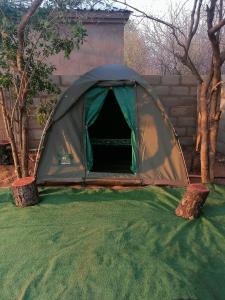 a green tent sitting on top of a grass field at Looks cottages self catering apartments in Kasane