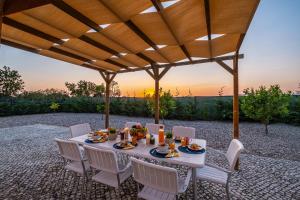 ein Tisch und Stühle unter einer Pergola mit Sonnenuntergang in der Unterkunft Villa Paradise by Algarve Vacation in Lagoa