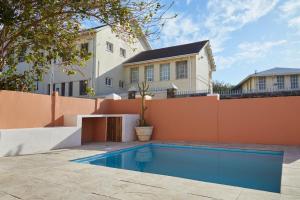 a house with a swimming pool in front of a fence at City Club Guesthouse in Cape Town