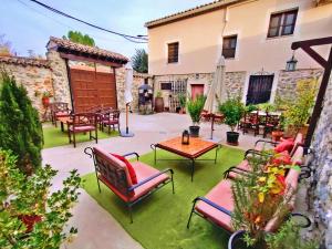 a patio with chairs and tables and a building at Casa Rural El Cencerro in Villamanrique de Tajo