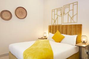 a bedroom with a bed with a yellow blanket on it at City Club Guesthouse in Cape Town