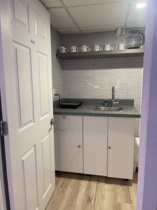 a kitchen with white cabinets and a sink and a door at Fully Furnished CozyTwo Bedroom in Winnipeg