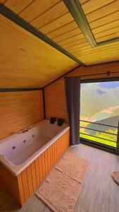 a large bath tub in a room with a large window at Panorama Otel in Uzungol