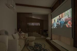 a woman sitting on a couch in a living room with a tv at Jeonju Hanok Village, Maison14 in Jeonju