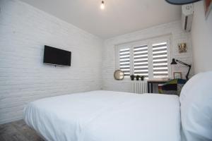 um quarto branco com uma cama e uma televisão de ecrã plano em Art Studio 2 em Tashkent