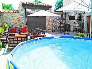 una piscina en un patio con sillas y sombrilla en Casa Rural El Cencerro, en Villamanrique de Tajo