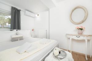 - une chambre blanche avec un grand lit blanc et un miroir dans l'établissement Livingstone Cottage by A&D Properties, à Pórto Ráfti