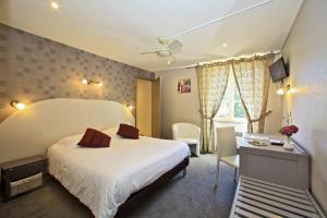 a bedroom with a bed and a desk and a window at Logis La Vieille Auberge, Art and Gallery in Souillac