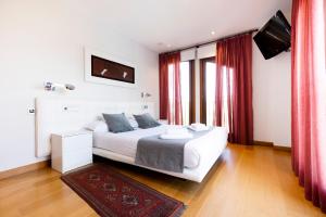 a bedroom with a large white bed with red curtains at Villa Elisa by Basquelidays in Hondarribia