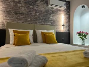 a bedroom with a bed with yellow pillows and a brick wall at Arena Prestige Rooms in Pula