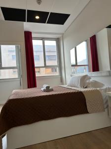 - une chambre avec un grand lit dans une pièce dotée de fenêtres dans l'établissement Aparthotel Montcada, à Montcada i Reixac
