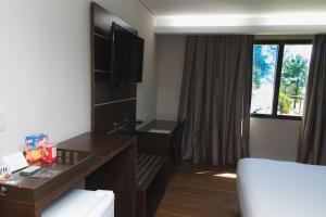 Habitación de hotel con cama, escritorio y ventana en Awa Resort Hotel, en Encarnación