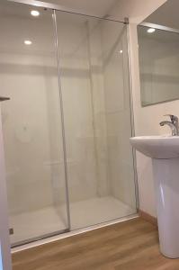 a shower with a glass door next to a sink at Aparthotel Montcada in Montcada i Reixac