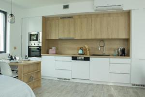 a kitchen with white and wooden cabinets and a desk at Apartmán X28 in Mikulov