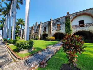 un ancien bâtiment avec des palmiers et de l'herbe verte dans l'établissement Hotel Hacienda Vista Hermosa, à Tequesquitengo
