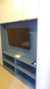 a tv on a shelf with a blue wall at Flat em Boa Viagem - Edifício Rooftop 470 in Recife