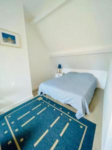 um quarto com uma cama e um tapete azul em Cottage Malenkiy ( piscine chauffée 15/06-15/09 ) em Cabourg