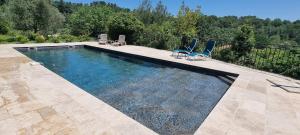 una piscina con 2 sillas azules en Idylle à 2, Sauna & Piscine, en Varages