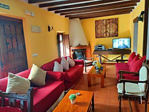 a living room with red couches and a piano at Casa Rural El Cencerro in Villamanrique de Tajo