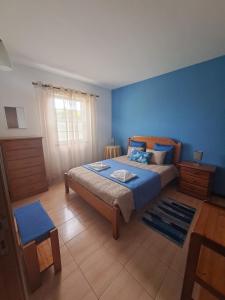 Vila Flor في Lajes das Flores: غرفة نوم بسرير وجدار ازرق