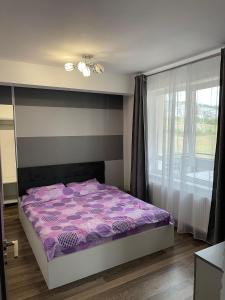 ein Schlafzimmer mit einem lila Bett und einem Fenster in der Unterkunft YamaLuxe Apartments - WestSide in Floreşti