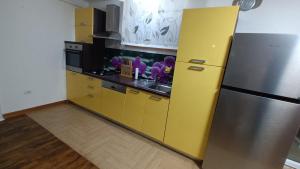 a kitchen with yellow cabinets and a stainless steel refrigerator at Vile Park Apartments Pula in Pula