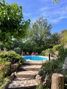 una piscina con un camino de piedra que conduce a un jardín en La Parenthèse du Var - Chambre d'hôtes petits déjeuners inclus et terrasse ombragée, en Saint Antonin du Var
