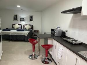 a bedroom with a bed and a kitchen with red stools at Departamento Merced in Quillota
