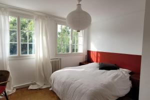a bedroom with a white bed and two windows at Casateja Houlgate in Houlgate